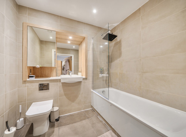 Bathroom with bathtub, shower, toilet, sink, and wall mirror.