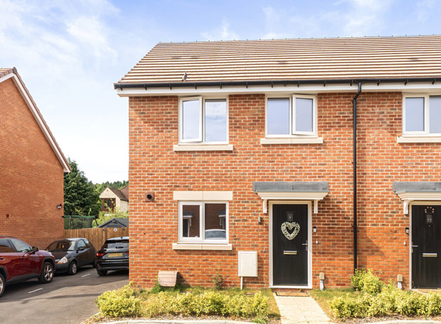 Red brick semi-detached house exterior with front door, windows, and small front garden.