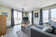 Living room with sofas, coffee table, television, and windows.