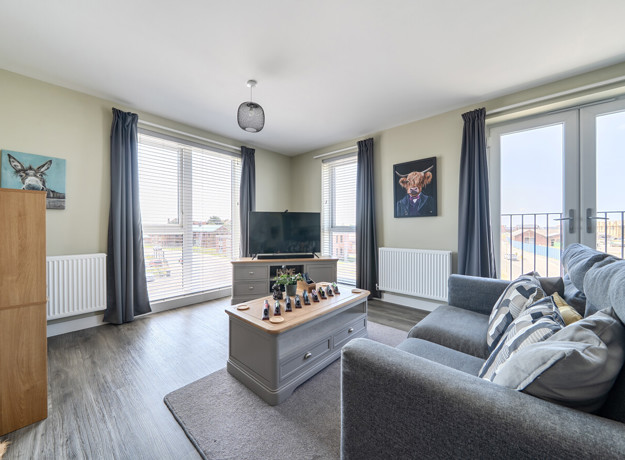 Living room with sofas, coffee table, television, and windows.