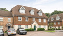 Row of brick terraced houses with parked cars in a shared driveway.