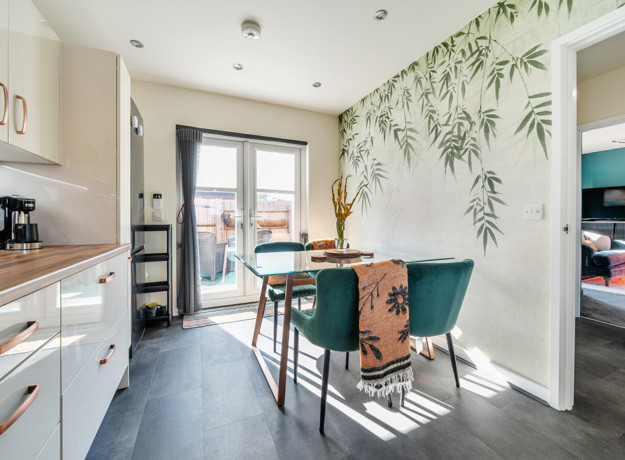 Kitchen and dining area with table, chairs, wall mural and patio doors.