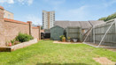 Back garden with lawn, fence panels, shed and surrounding buildings.