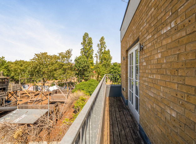 Side view from the balcony showing a brick wall and surrounding trees.