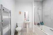Bathroom with toilet, pedestal sink, bathtub and shower screen.