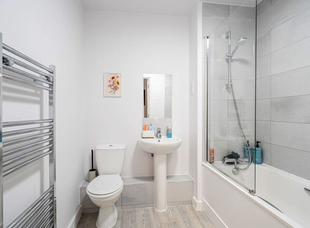 Bathroom with toilet, pedestal sink, bathtub and shower screen.