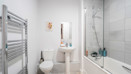 Bathroom with toilet, pedestal sink, bathtub and shower screen.
