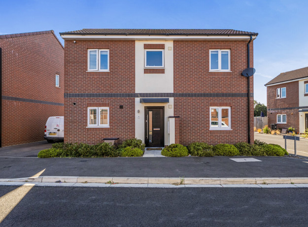 Detached brick house with front entrance and surrounding pavement.