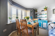 Dining space with wooden table and chairs positioned by bay windows and shelving