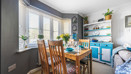 Dining space with wooden table and chairs positioned by bay windows and shelving