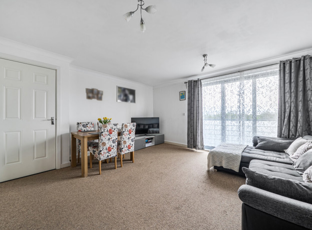 Living room with sofas, dining table and chairs, carpet, and balcony door with curtains.