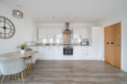 Kitchen and dining area with white cabinets, appliances, wood-effect flooring, and dining table