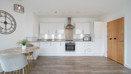 Kitchen and dining area with white cabinets, appliances, wood-effect flooring, and dining table