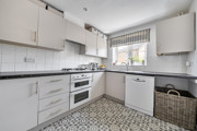 Kitchen with white cabinets, integrated oven, worktops and a window.