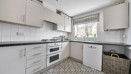 Kitchen with white cabinets, integrated oven, worktops and a window.