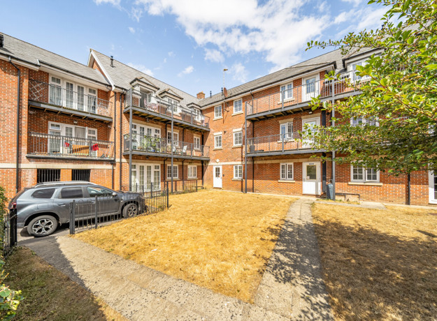 Apartment building courtyard with parked cars and landscaped area.