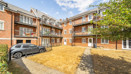 Apartment building courtyard with parked cars and landscaped area.