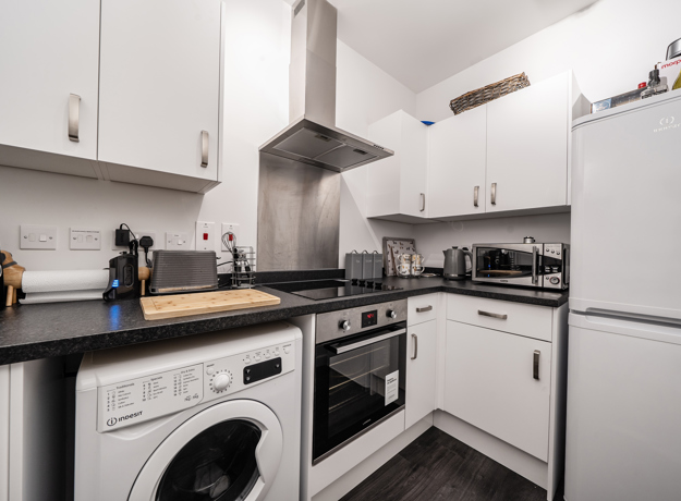 Kitchen with white cabinets, appliances, and dark worktops