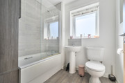 Bathroom with bathtub, toilet, sink, and frosted window.