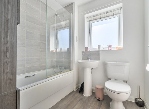 Bathroom with bathtub, toilet, sink, and frosted window.