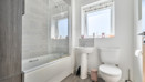 Bathroom with bathtub, toilet, sink, and frosted window.