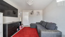 Living room with grey sofa, wall-mounted TV, and red carpet flooring.