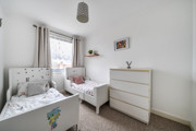 Children's bedroom with two single beds, dresser, and wall pictures.