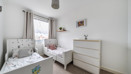 Children's bedroom with two single beds, dresser, and wall pictures.