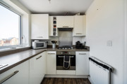 Kitchen with worktops, storage units and integrated oven.