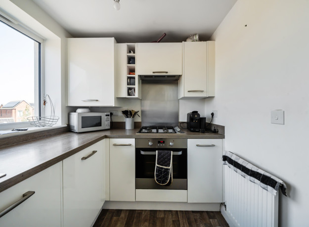 Kitchen with worktops, storage units and integrated oven.