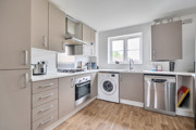 Modern kitchen with beige cabinets, appliances and wooden-effect floor.