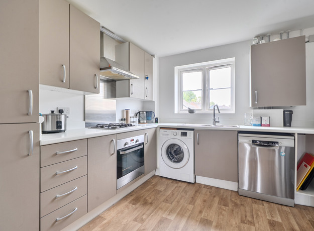 Modern kitchen with beige cabinets, appliances and wooden-effect floor.