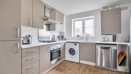 Modern kitchen with beige cabinets, appliances and wooden-effect floor.
