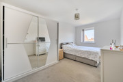 Bedroom with mirrored wardrobe, bed, and chest of drawers.
