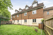 Rear view of terraced houses with lawn garden and fenced boundary.