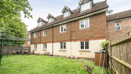 Rear view of terraced houses with lawn garden and fenced boundary.