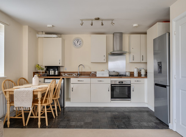 Open plan kitchen and dining area with table, chairs, appliances and fitted cabinets.