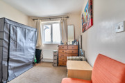 Single bedroom in a modern home with window, carpeted flooring, chest of drawers and built-in storage space.