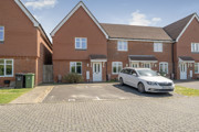 Row of modern red brick houses with driveway parking on a residential estate