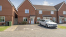 Row of modern red brick houses with driveway parking on a residential estate