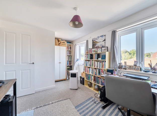 Home office with desk, shelving unit and large window.