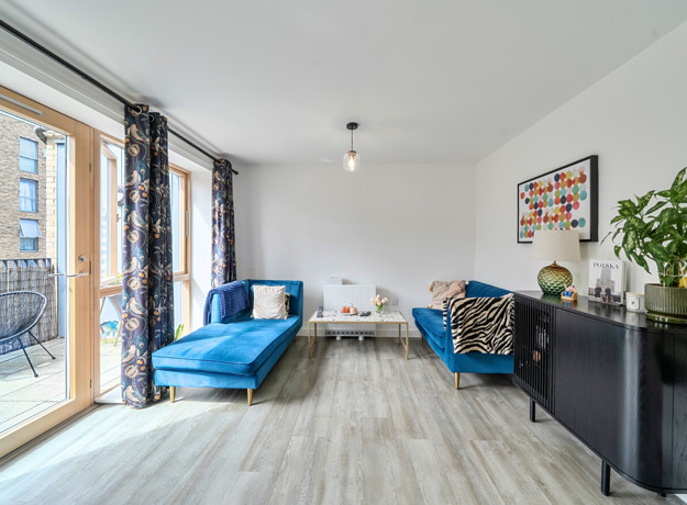 Living room with seating, curtains and balcony access.