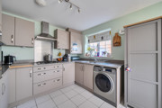 Kitchen with fitted cabinets, washing machine and tiled floor.