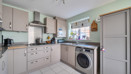 Kitchen with fitted cabinets, washing machine and tiled floor.