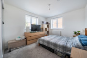 Bedroom with double bed, chest of drawers, TV and windows.