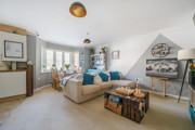Open plan living and dining area with neutral decor, sofa seating and natural daylight