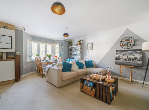 Open plan living and dining area with neutral decor, sofa seating and natural daylight