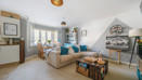 Open plan living and dining area with neutral decor, sofa seating and natural daylight