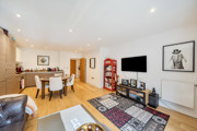 Open-plan living and kitchen area with television, sofas, and dining table.