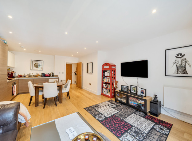 Open-plan living and kitchen area with television, sofas, and dining table.